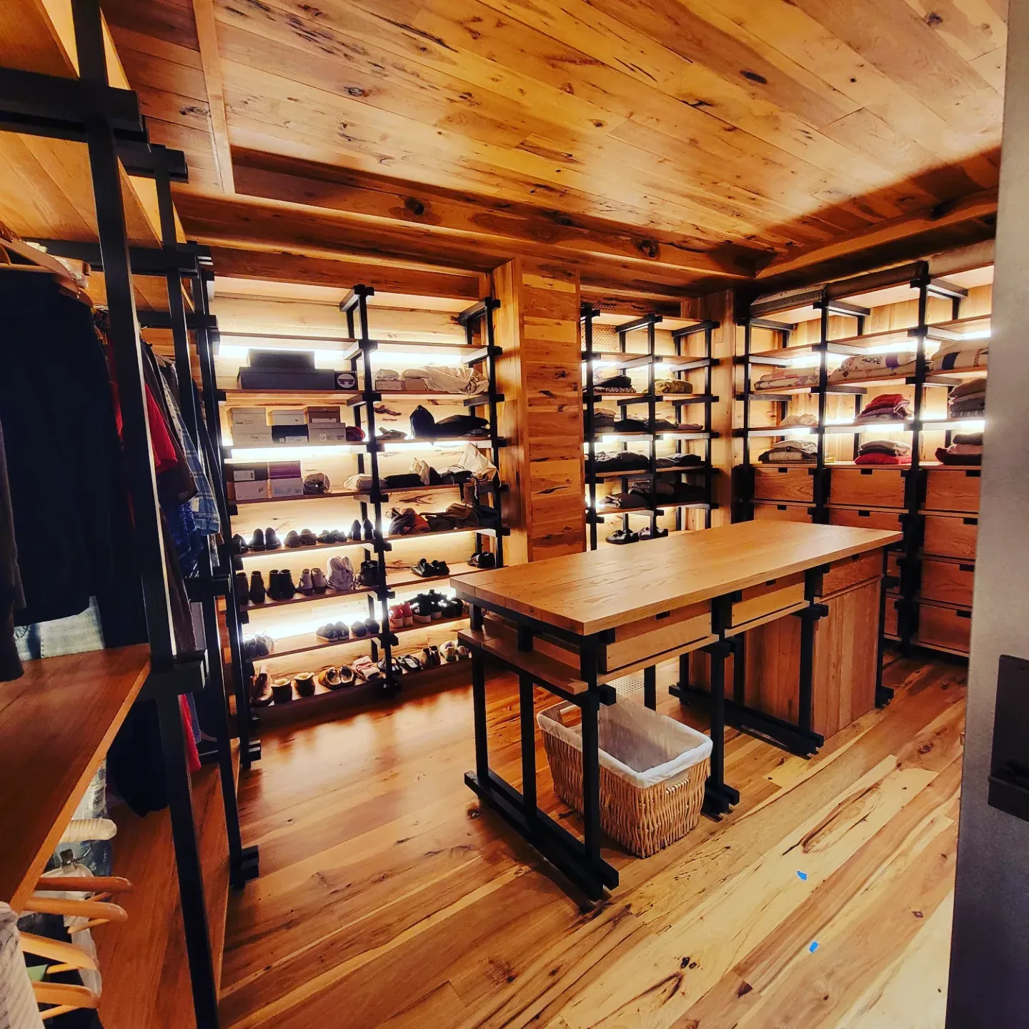 Custom reclaimed-wood dressing room with hardwood floor and lit shelving